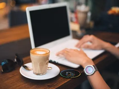Tarjeta NFC de reseñas de Google sobre la mesa de una cafetería, junto a un café y un portátil