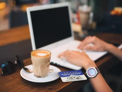 Tarjeta NFC de reseñas de Google sobre la mesa de una cafetería, junto a un café y un portátil